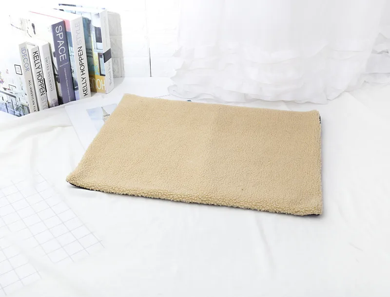 Tan fleece pet mat laid on a bed beside books