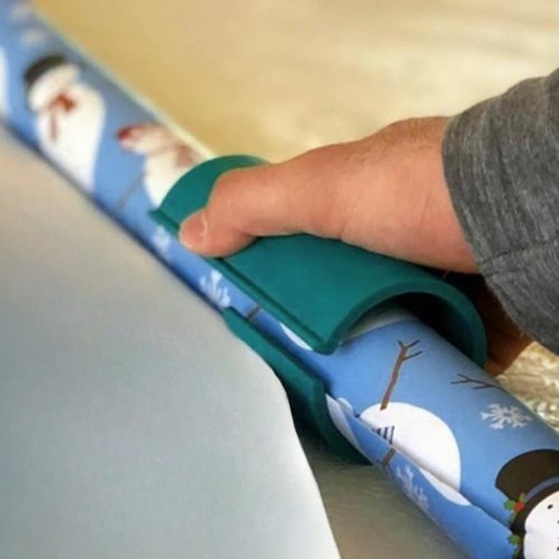 Gift wrap cutter sliding along a roll of Christmas wrapping paper